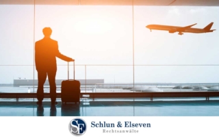 Man with small suitcase at airport watching plane flying.